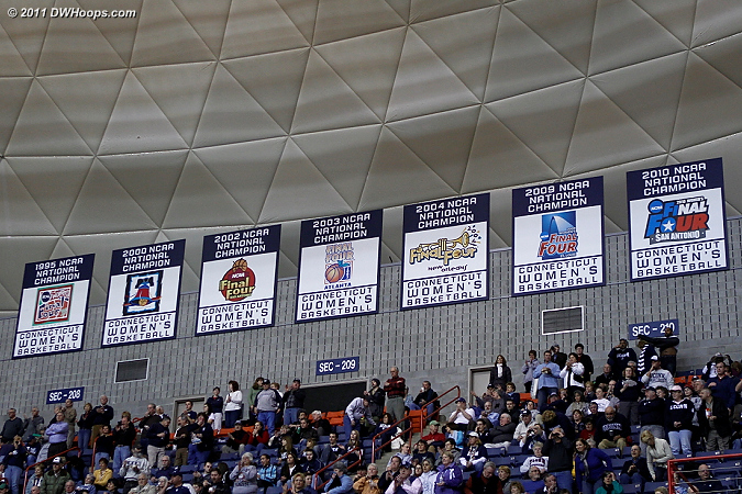 Gampel Pavilion is ringed with signs and banners lauding both UConn basketball programs, capped by the Women's National Champs section  