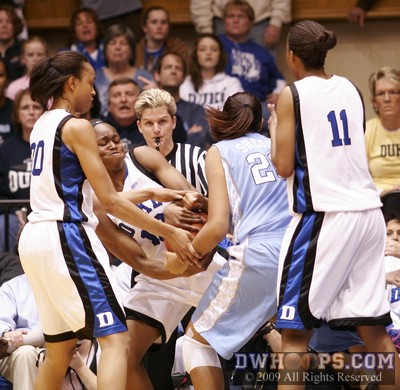 Referee Jennifer Rezac is right in the middle of a held ball between Karima Christmas and Chay Shegog - arrow favors Duke